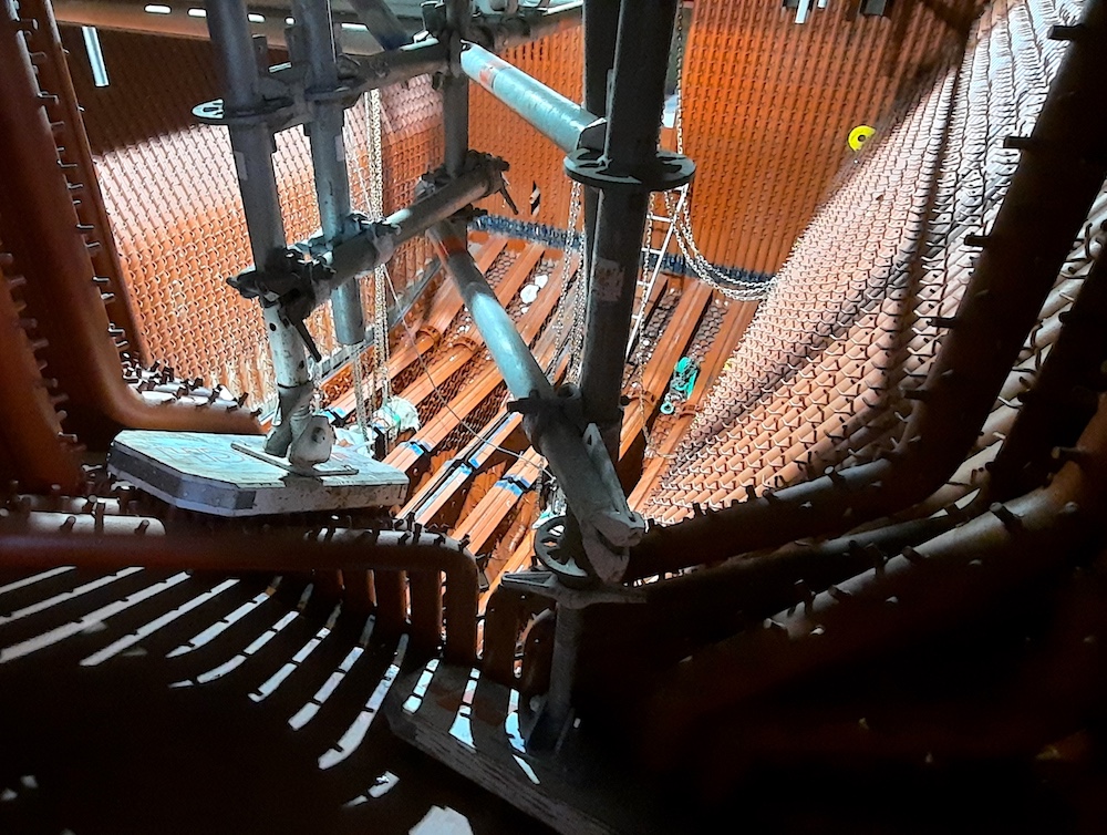 Interior view of a bubbling fluidized bed (BFB) biomass boiler during construction, showing the gas distributor, membrane waterwall tubes, and furnace prepared for refractory installation.